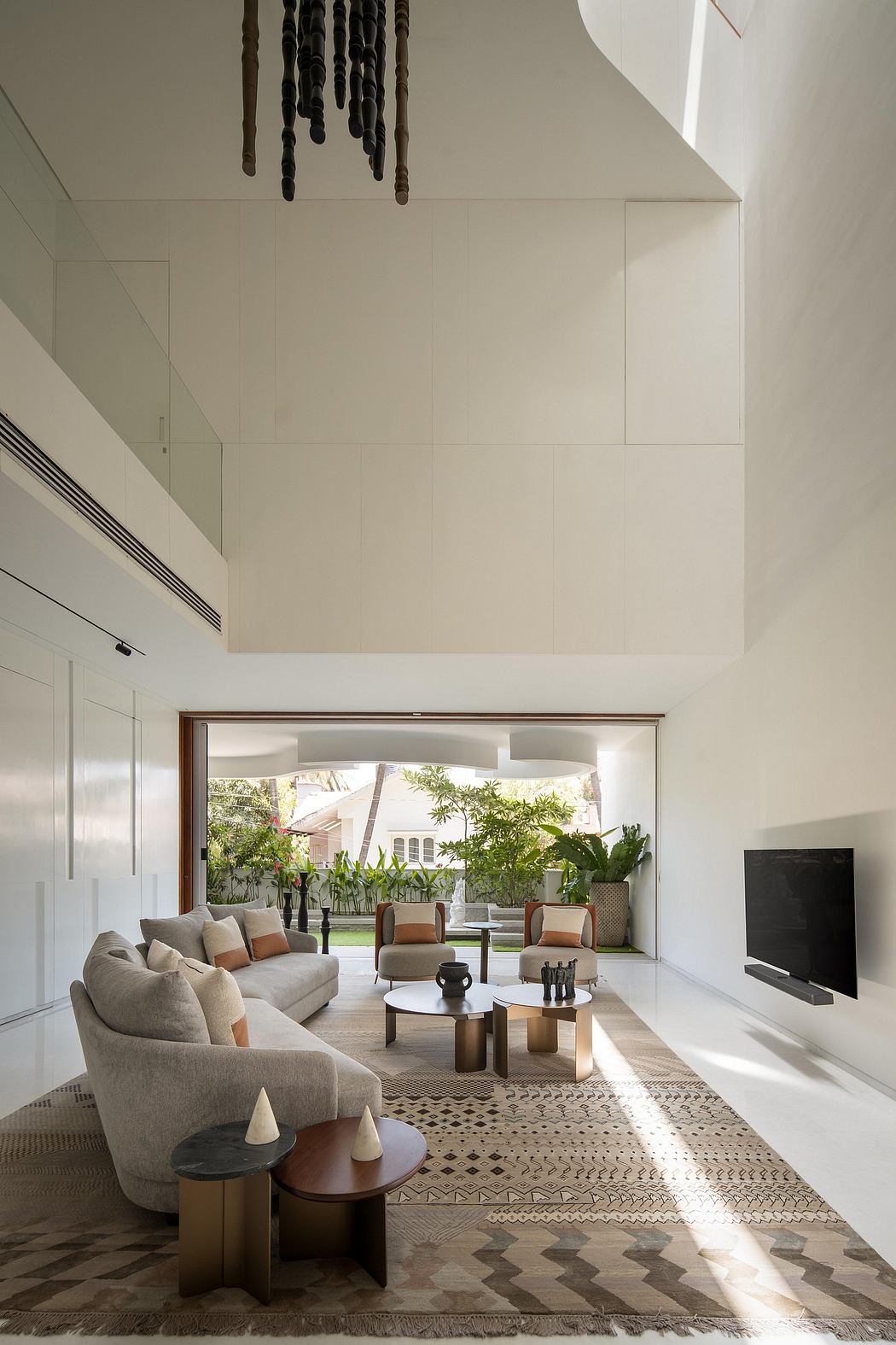 Minimalist living room with large windows, textured rug, and sculptural furnishings.