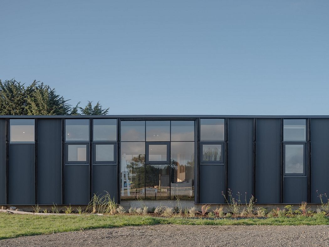 Modern, sleek exterior with large windows and a minimalist black cladding system.