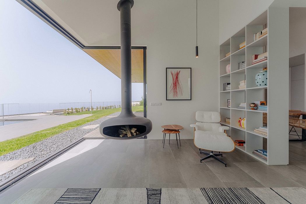 Modern architectural space with a central fireplace, shelving, and outdoor views.
