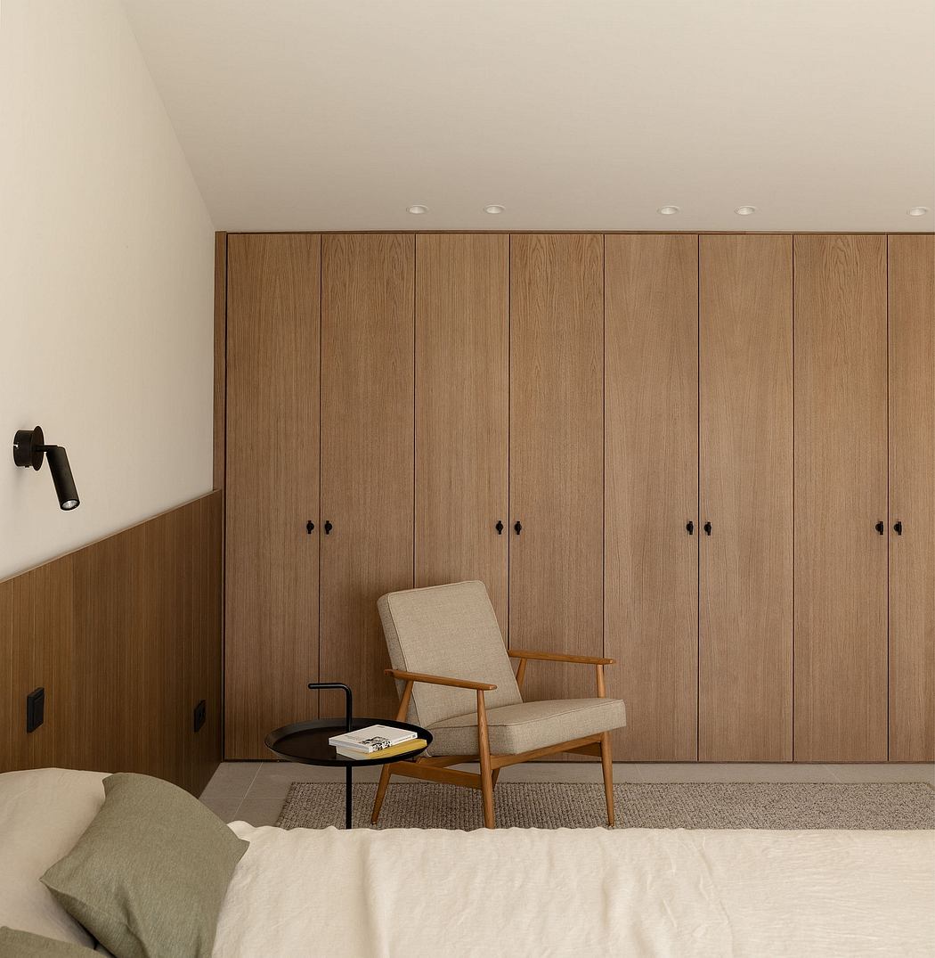 Minimalist bedroom with wood-paneled walls, modern armchair, and minimal decor.