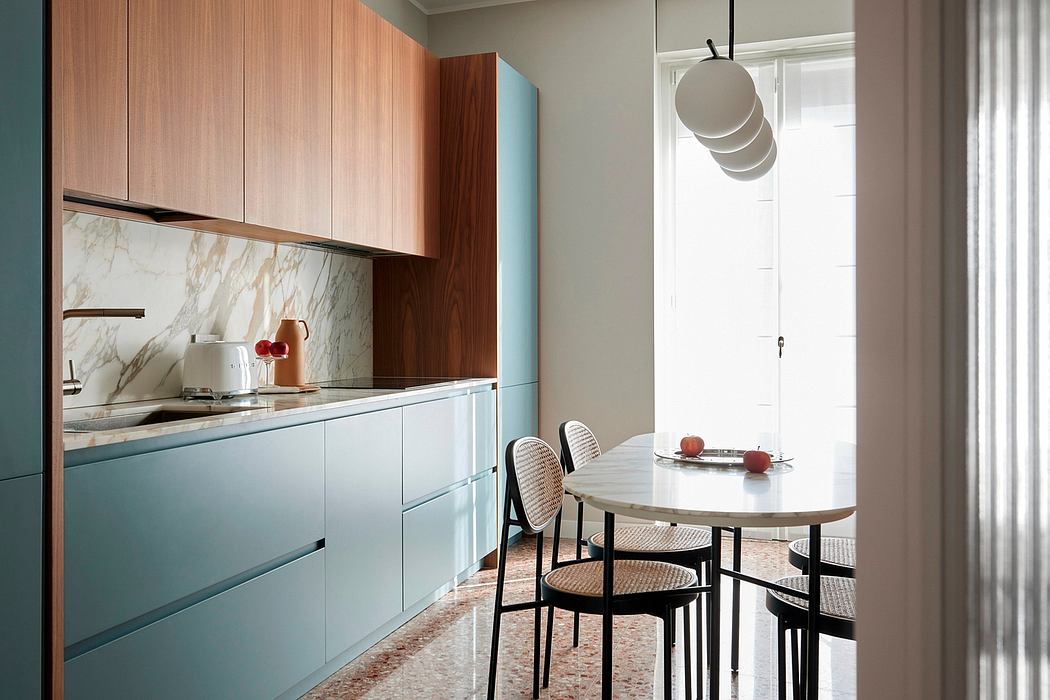 Modern kitchen with sleek blue cabinetry, marble backsplash, and round dining table.