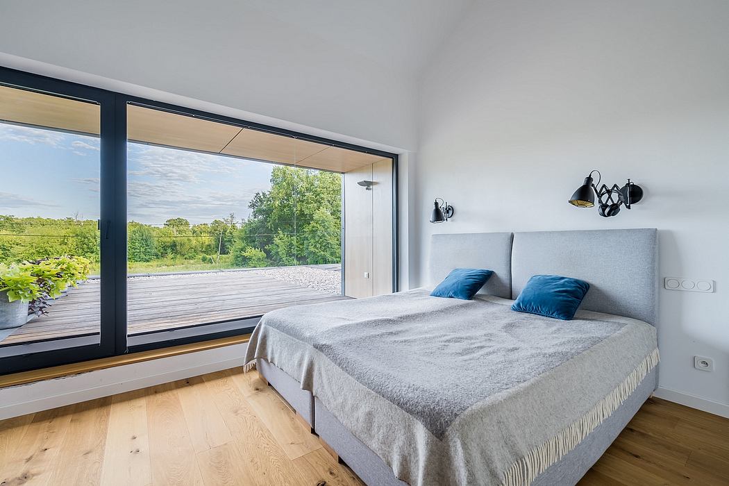 Modern, minimalist bedroom with large windows overlooking lush greenery outside.