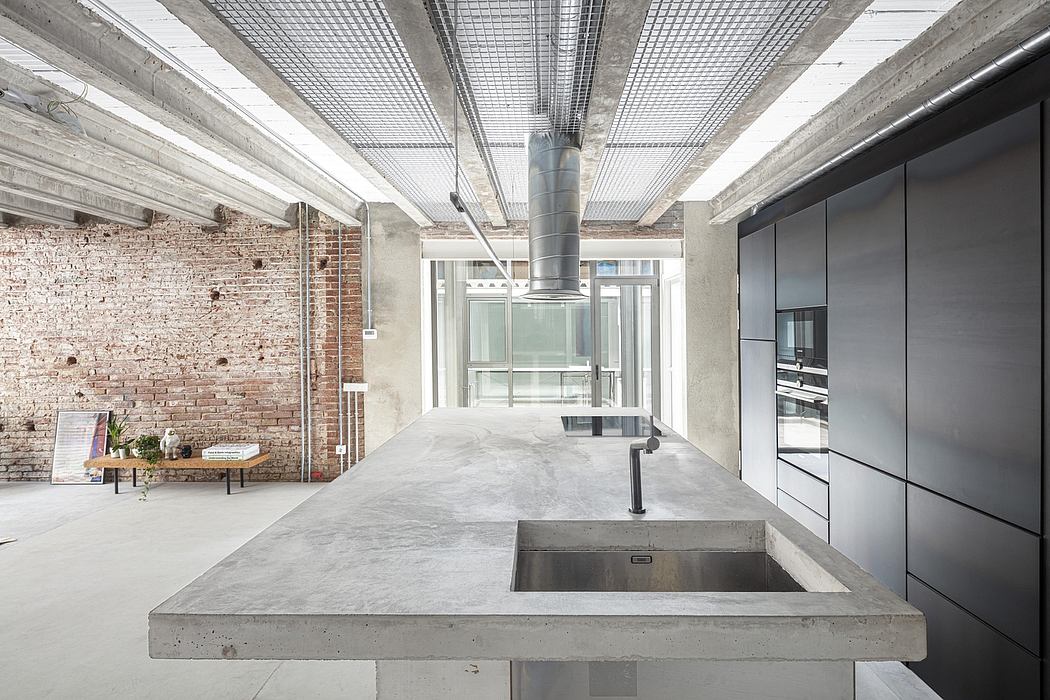 Minimalist industrial kitchen with exposed brick walls, concrete countertop, and metallic accents.