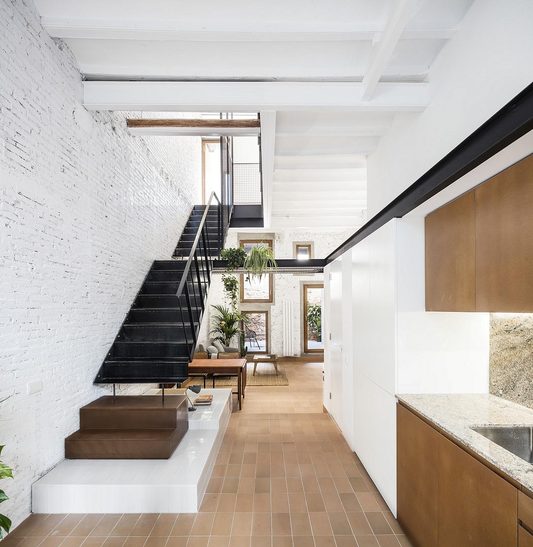 A modern, open-concept space featuring a sleek staircase and warm wooden accents.