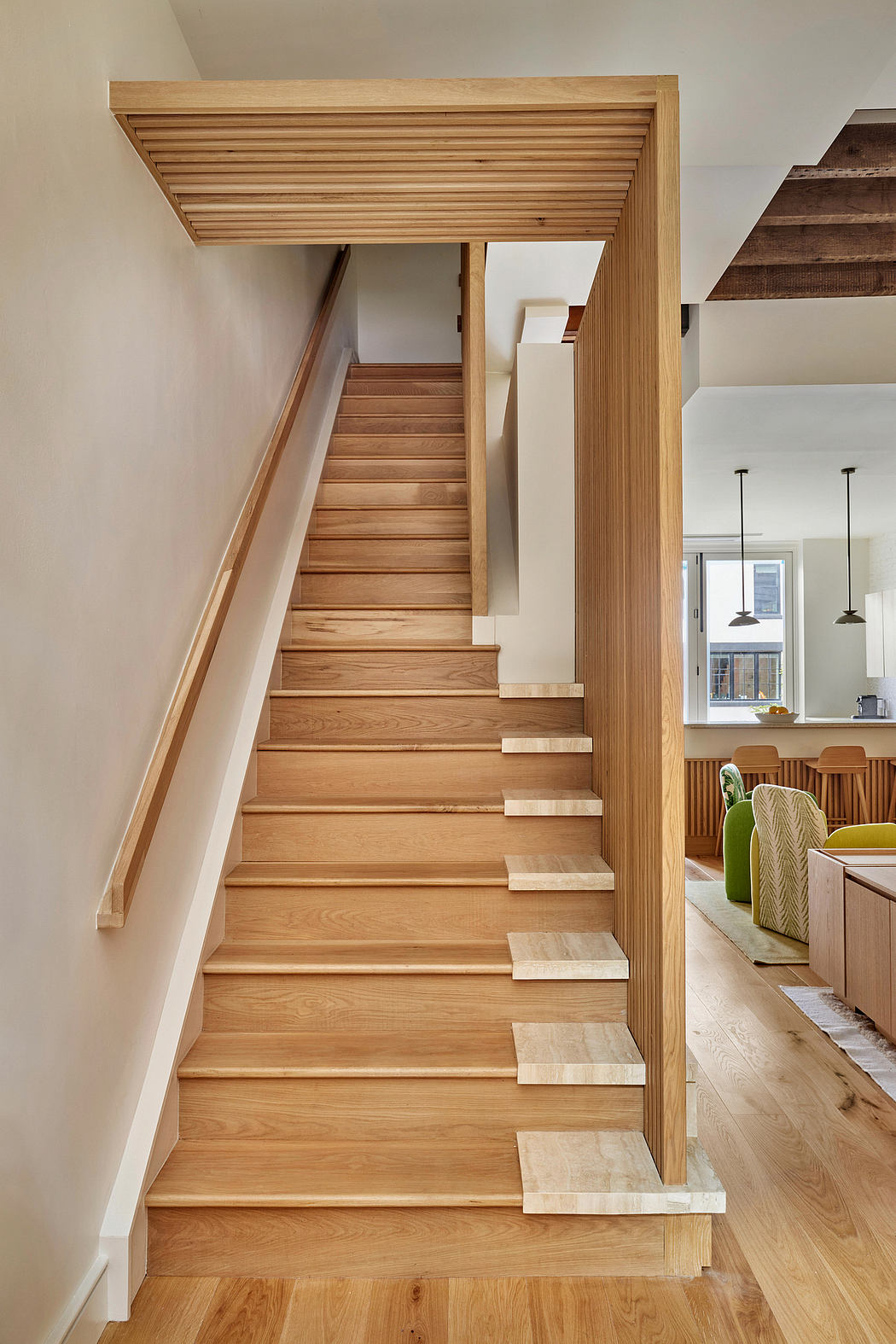 Wooden stairs with multilevel steps leading to an open-concept living space.