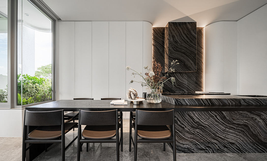 A modern dining room with a sleek black marble table and built-in cabinetry, framed by large windows.