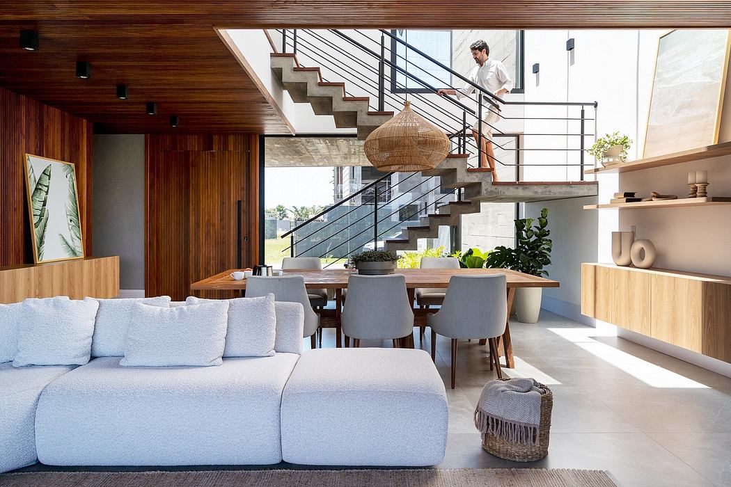 Modern, open-concept living space with wooden accents, hanging light fixture, and glass staircase.