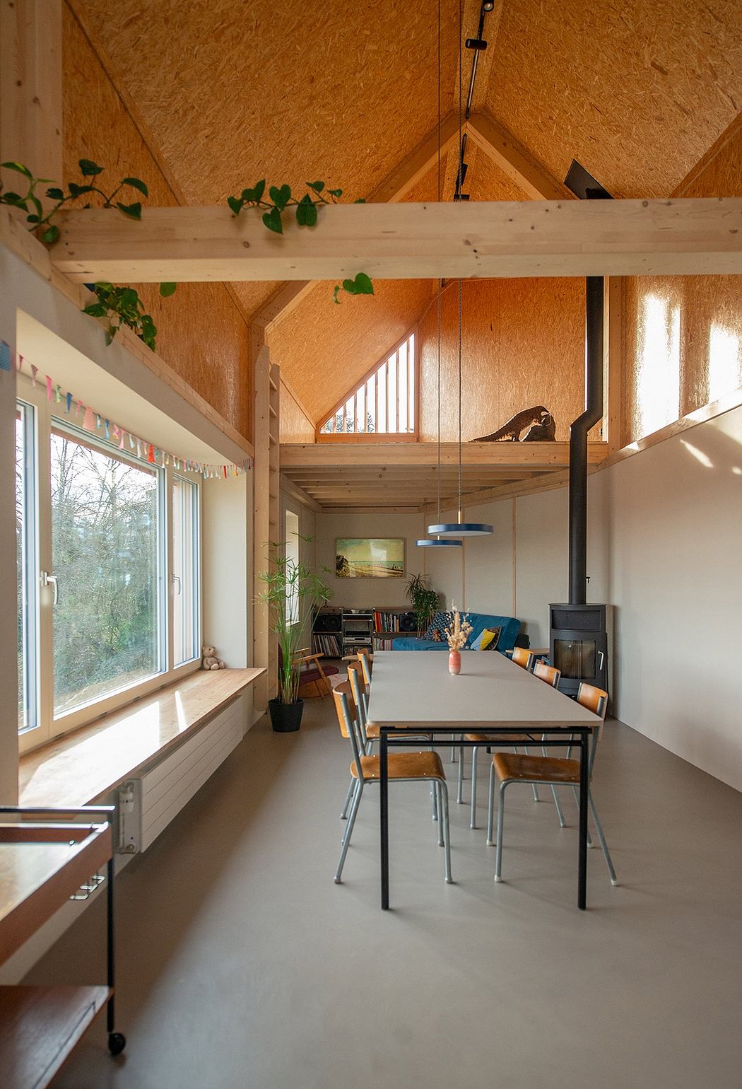 Warm, modern interior with exposed wood beams and vines, cozy seating area, and functional dining space.