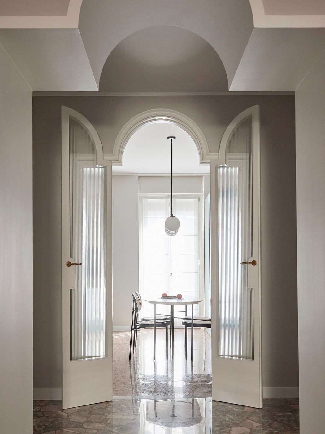 Elegant archway entry leads to a modern, minimalist dining space with a pendant light.