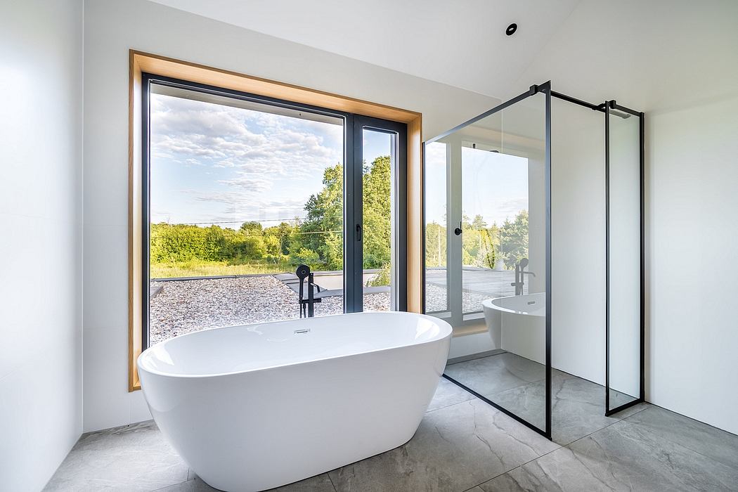 Spacious modern bathroom with a freestanding white tub, large window, and glass enclosure.