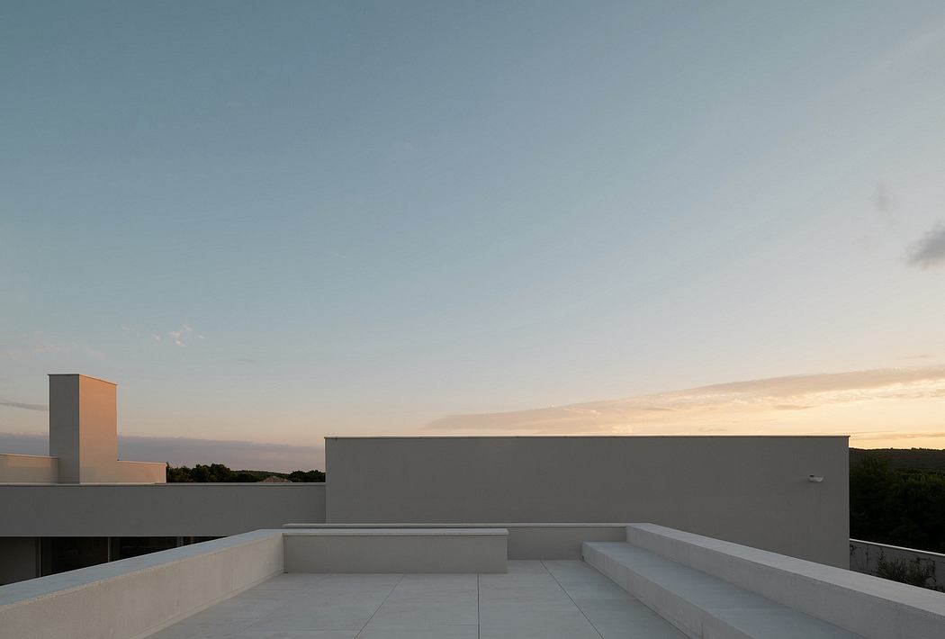 Minimalist architectural design with a concrete terrace, clean lines, and a serene sunset view.