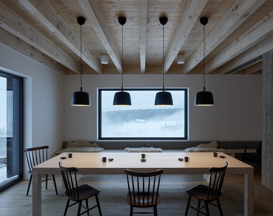 Rustic wooden beams, large window overlooking snowy landscape, modern pendant lights.
