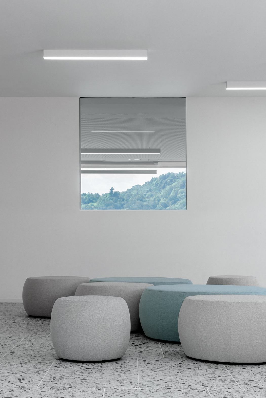 Modern, minimalist interior with geometric seating units and mountain view through large window.