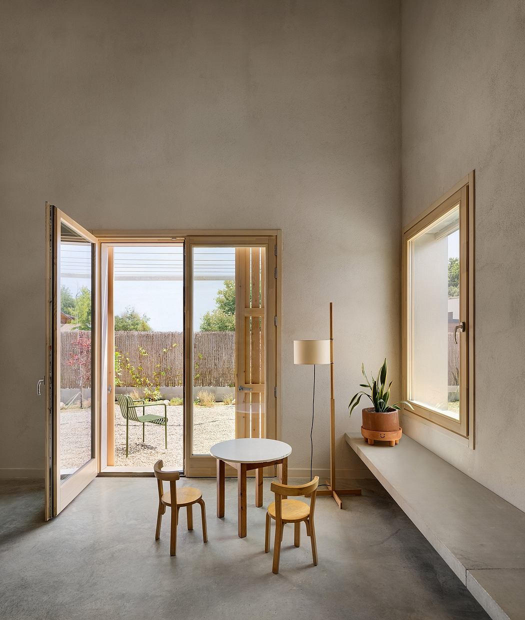 Cozy modern dining nook with glass doors, minimal furnishings, and potted plant.