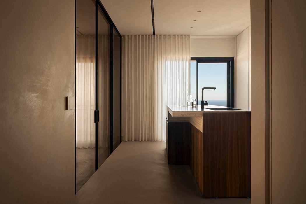 Sleek, minimalist kitchen with wood cabinetry and a view through large windows.