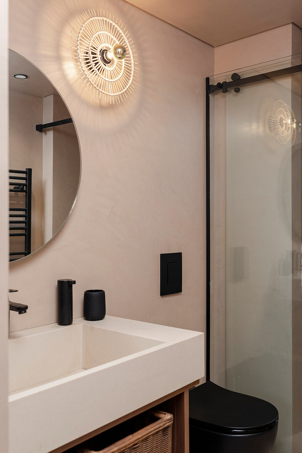 Stylish bathroom with a circular rattan light fixture, modern sink, and black accents.