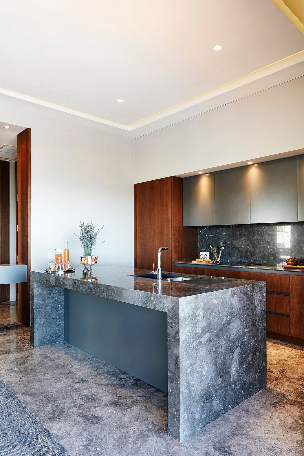 Sleek, modern kitchen with dark marble countertops, warm wood cabinetry, and recessed lighting.
