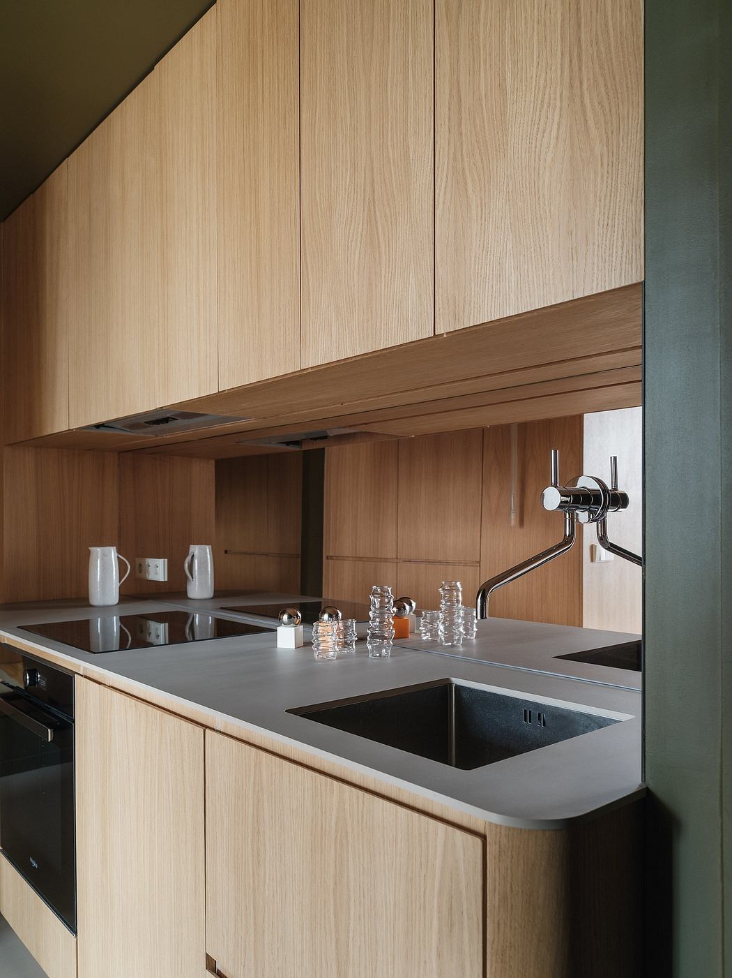 Sleek, modern kitchen design with wood cabinetry, black countertops, and streamlined fixtures.