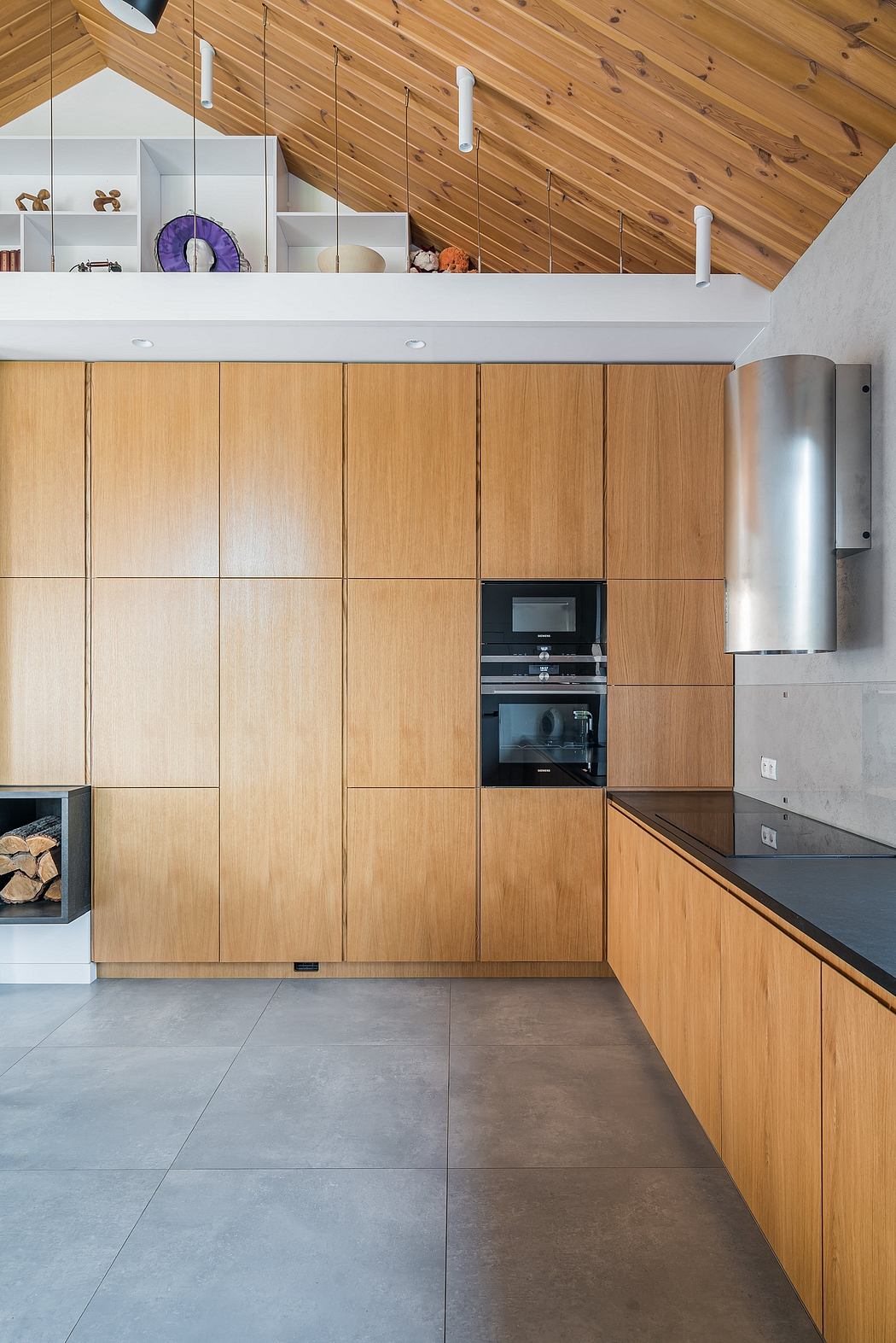 Sleek wooden cabinetry, recessed lighting, and concrete floors in modern kitchen.