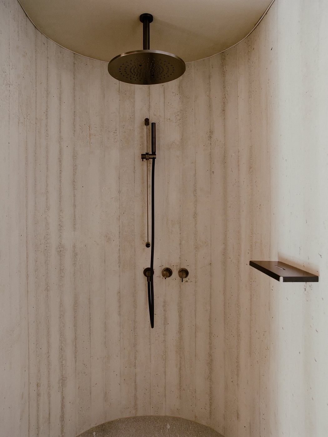 Sleek, modern shower with brushed bronze fixtures and concrete walls, minimalist design.