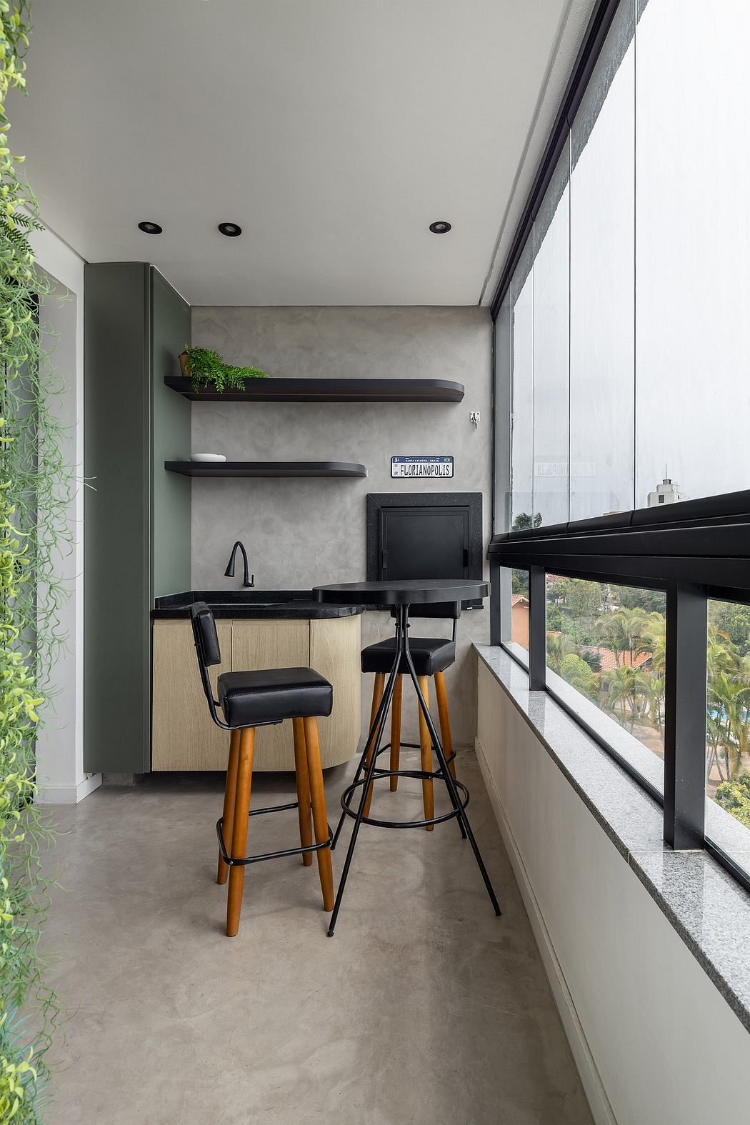 Sleek, modern kitchenette with black shelves, concrete walls, and wooden bar stools.