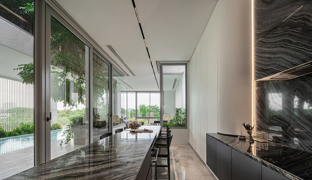 Spacious modern kitchen with floor-to-ceiling windows, sleek marble countertops, and linear lighting.