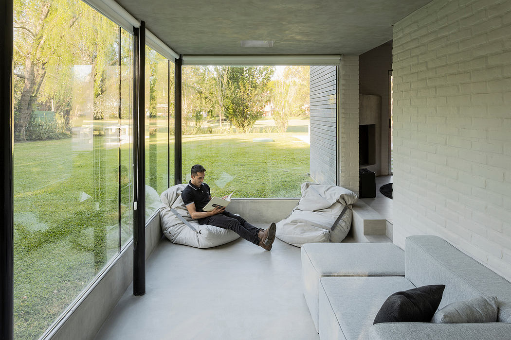 A modern, minimalist living room with large windows overlooking a lush green yard.