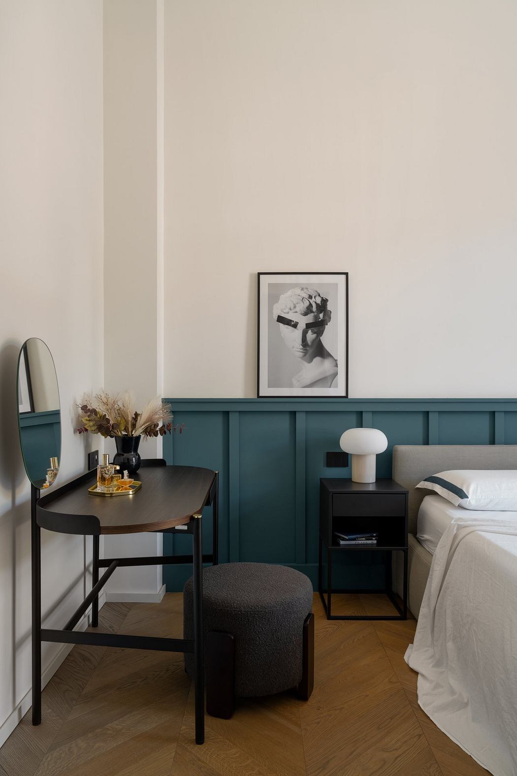 Minimalist bedroom with teal accent wall, black furniture, and framed artwork.