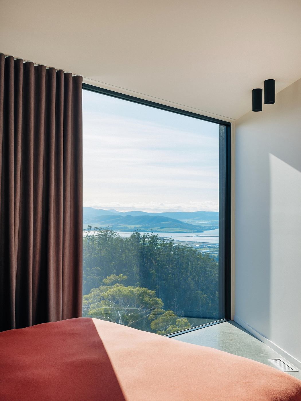 Expansive window offers breathtaking mountain and lake views, complemented by minimalist decor.