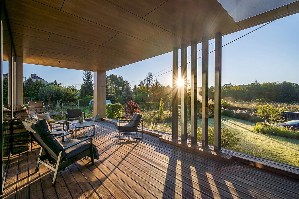 Spacious covered patio with wooden deck and seating area overlooking a lush, landscaped yard.