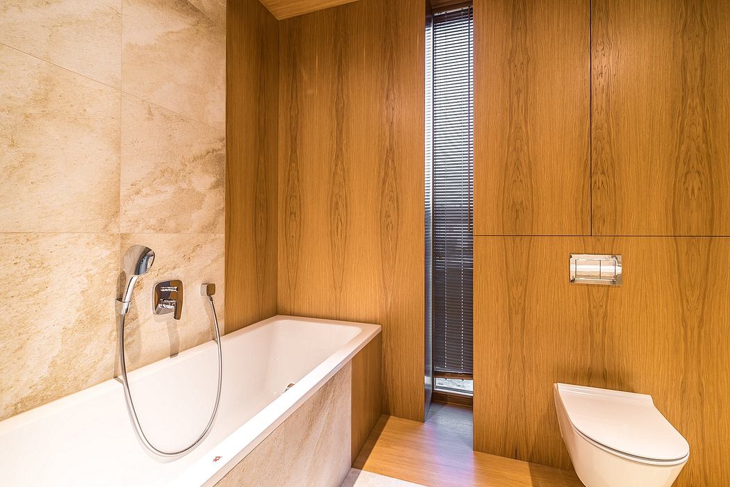 A modern, minimalist bathroom with a sleek tub, wooden paneling, and a window offering natural light.