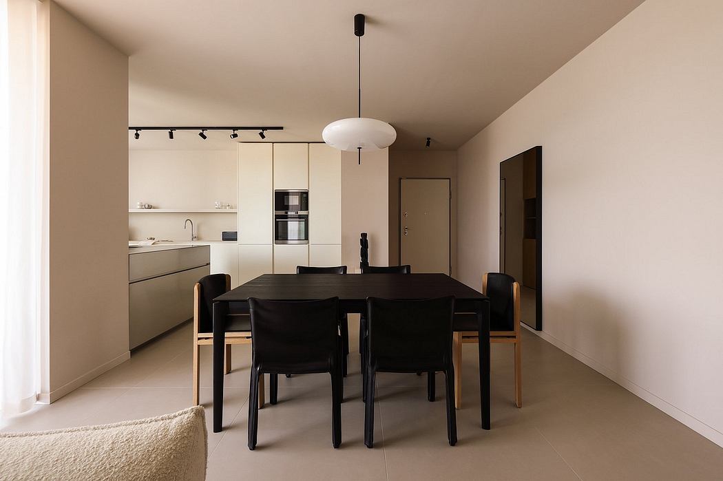 A modern, minimalist kitchen and dining area with sleek furniture and lighting.