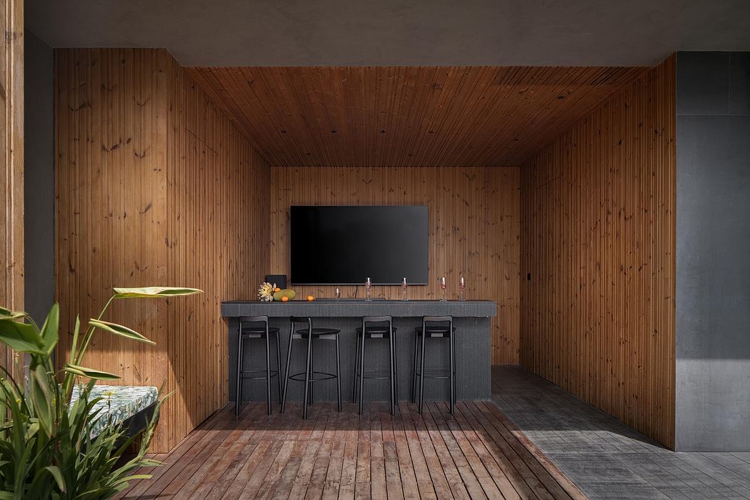 Warm, rustic wooden walls and floors contrast with a sleek black bar area and TV.