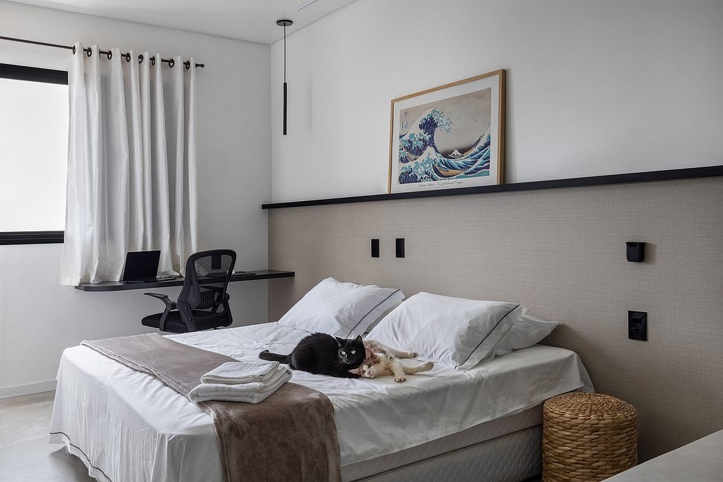 Modern bedroom with minimalist gray color scheme, artwork, and cat on the bed.