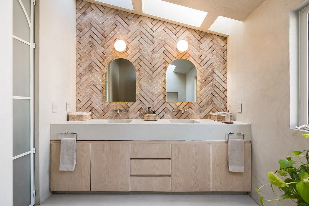 Spacious, modern bathroom with herringbone brick accent wall and dual vanities.