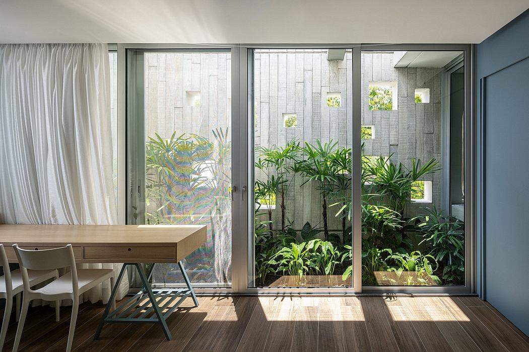 Minimalist living room with large glass doors, lush indoor plants, and wooden furniture.