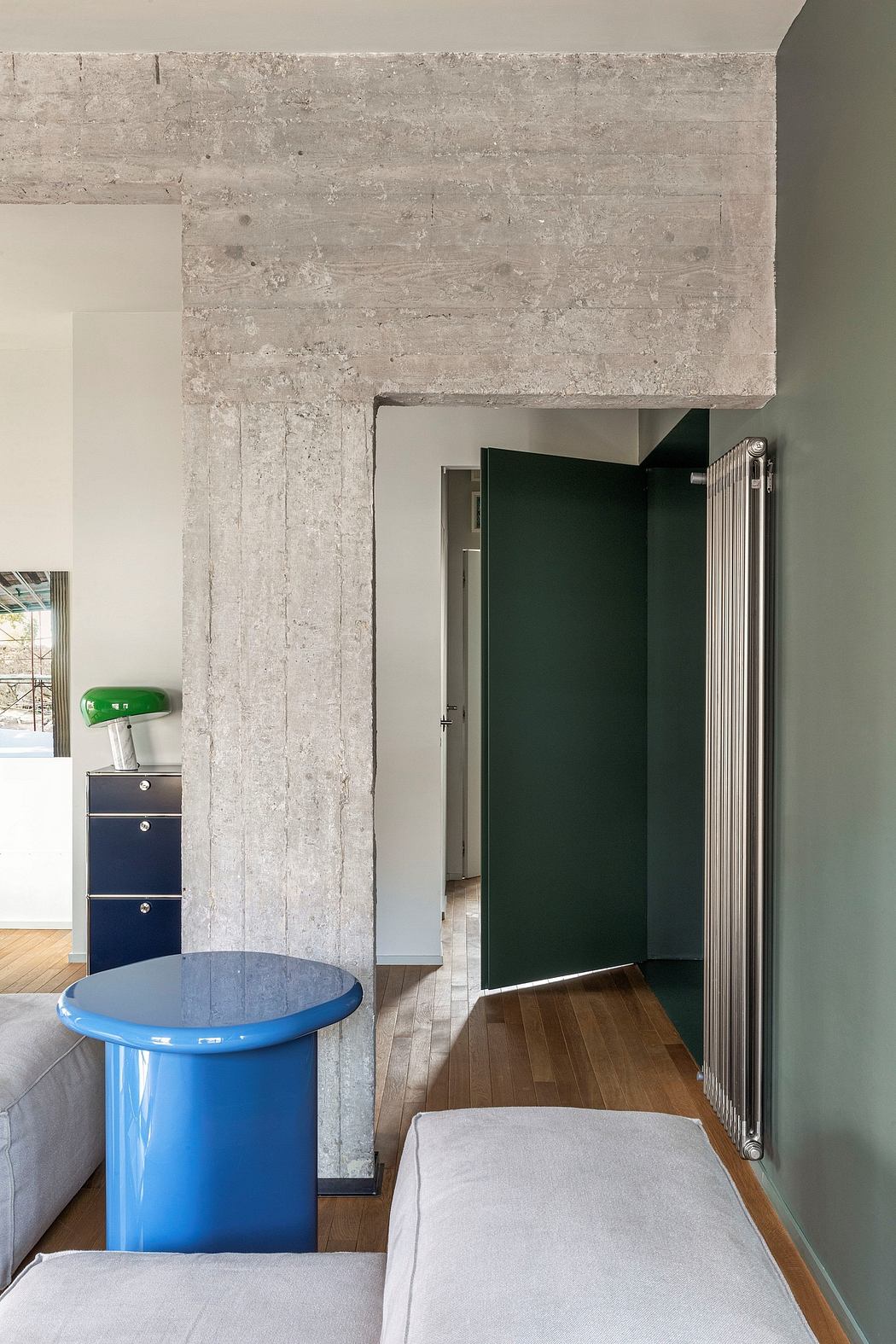 A modern room with concrete walls, wooden flooring, and a colorful storage unit.