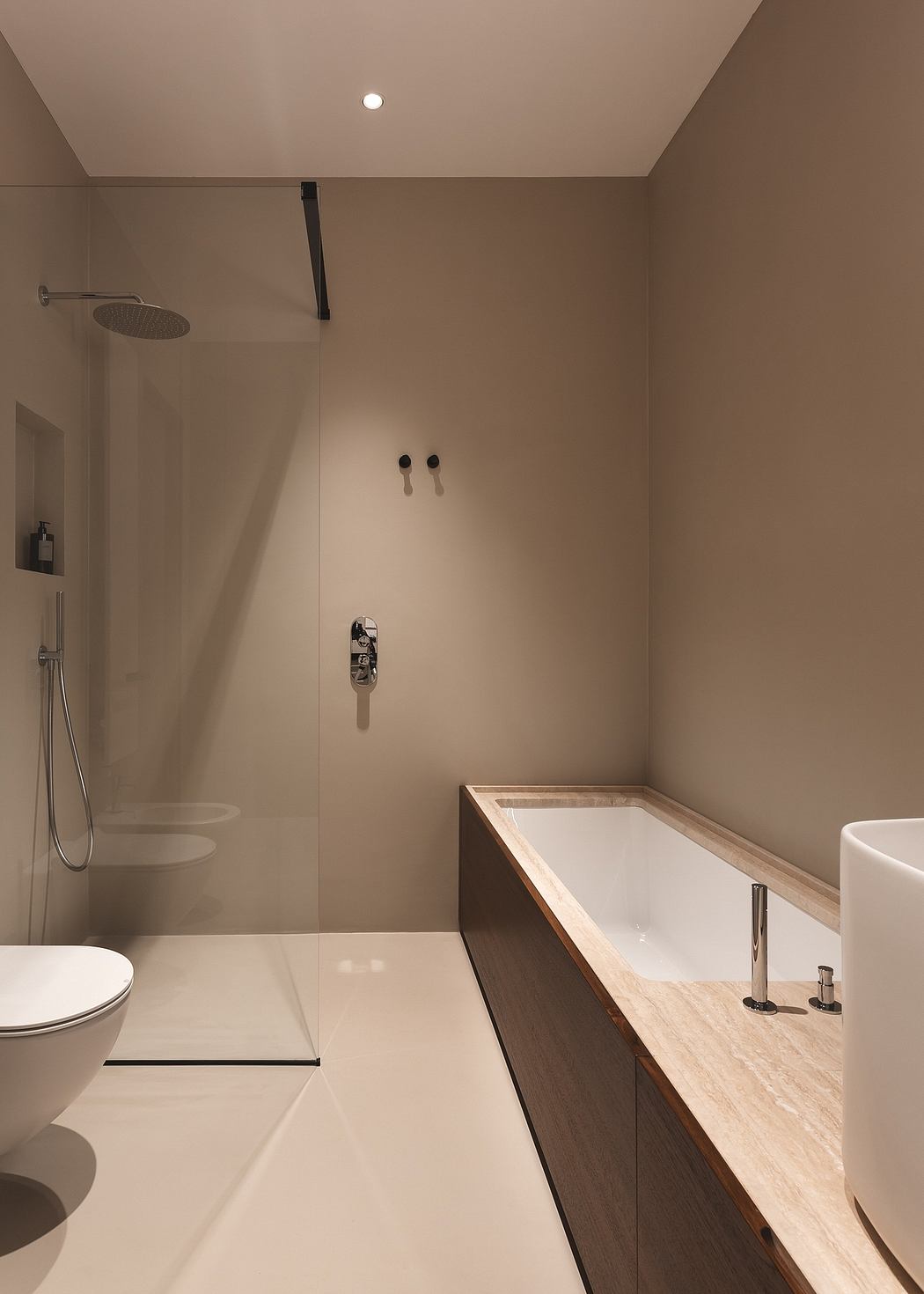 Minimalist bathroom design with wood vanity, white tile, and chrome fixtures.