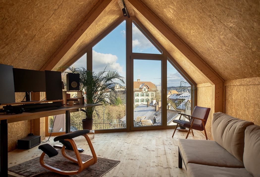 A cozy attic-like room with a large triangular window overlooking a cityscape.