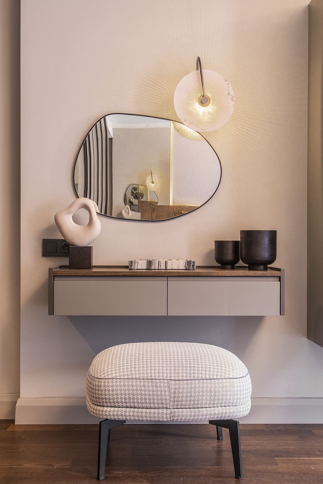 Minimalist vanity unit with oval mirror, lighting, and decorative vases and cushion.