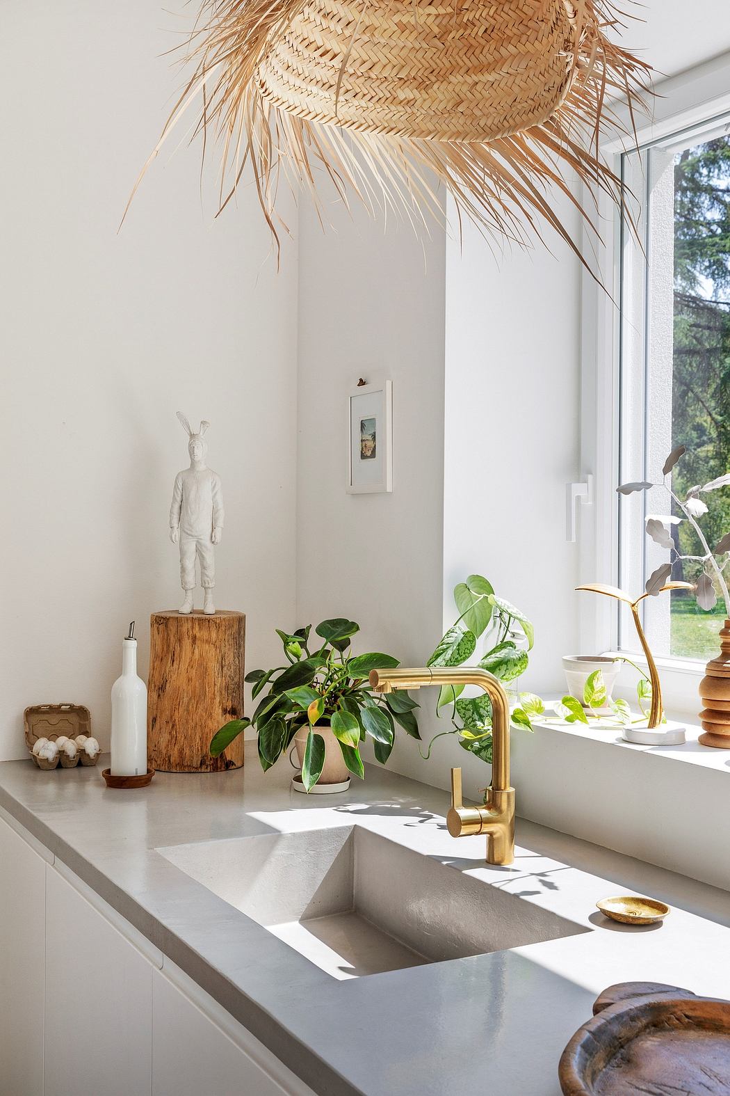 A modern bathroom with a large straw lampshade, potted plants, and a wooden pedestal.