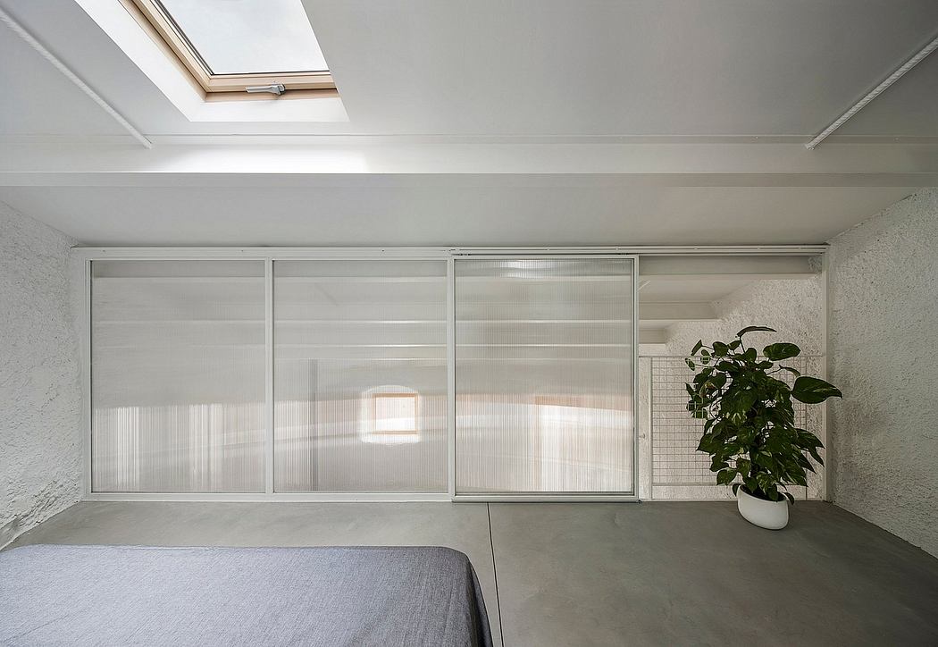 Modern interior with minimalist sliding glass panels, skylight, and plant decor.