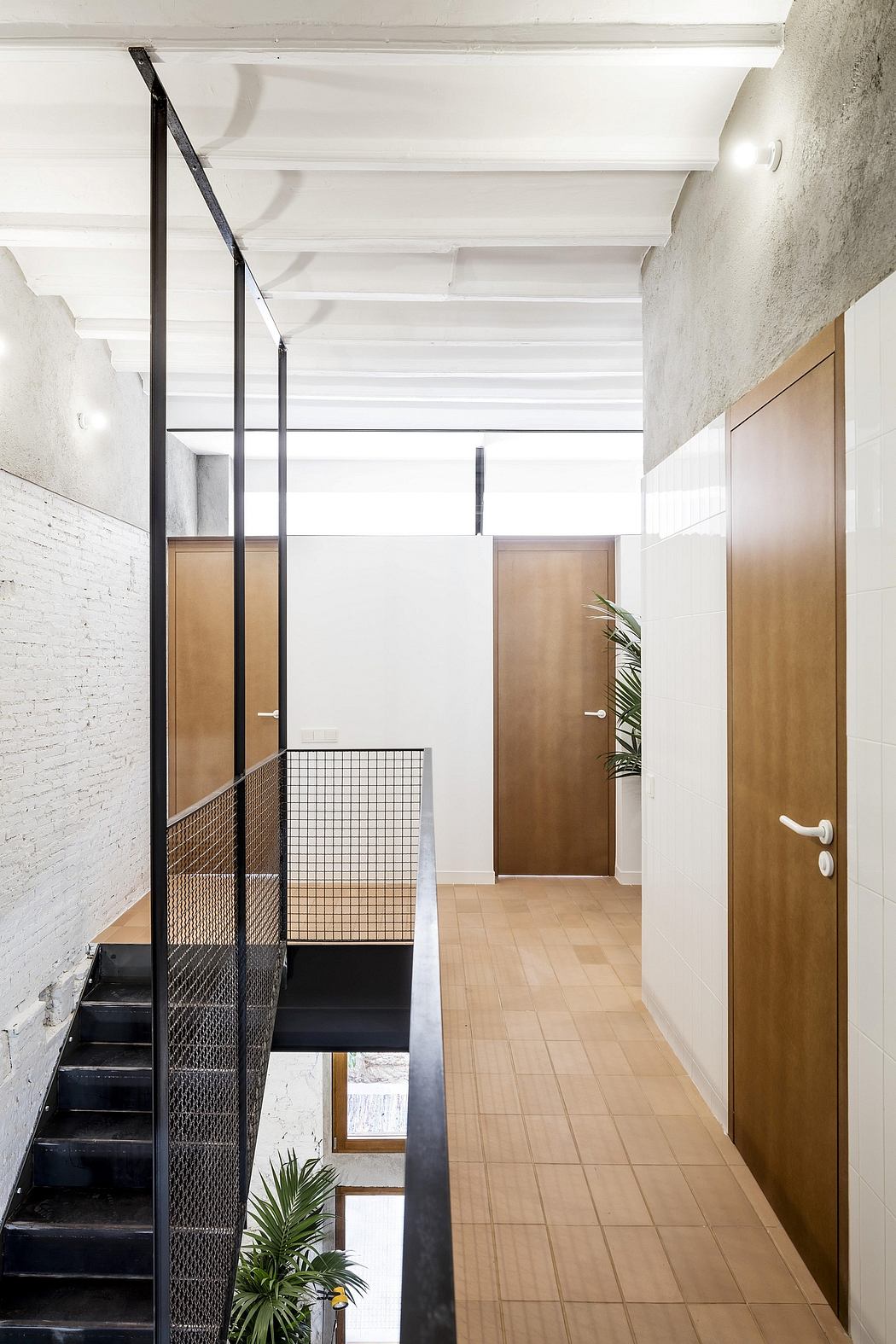 Minimalist hallway with exposed beams, metal railings, and wooden doors leading to other rooms.