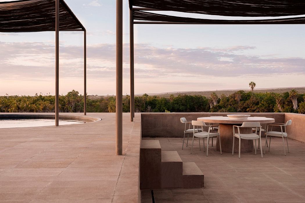 A modern, minimalist outdoor dining area with a panoramic view of a lush, tropical landscape.