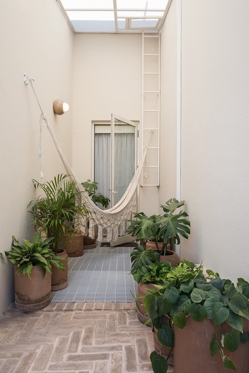 Cozy indoor patio with hammock, potted plants, and tiled flooring creating a serene atmosphere.