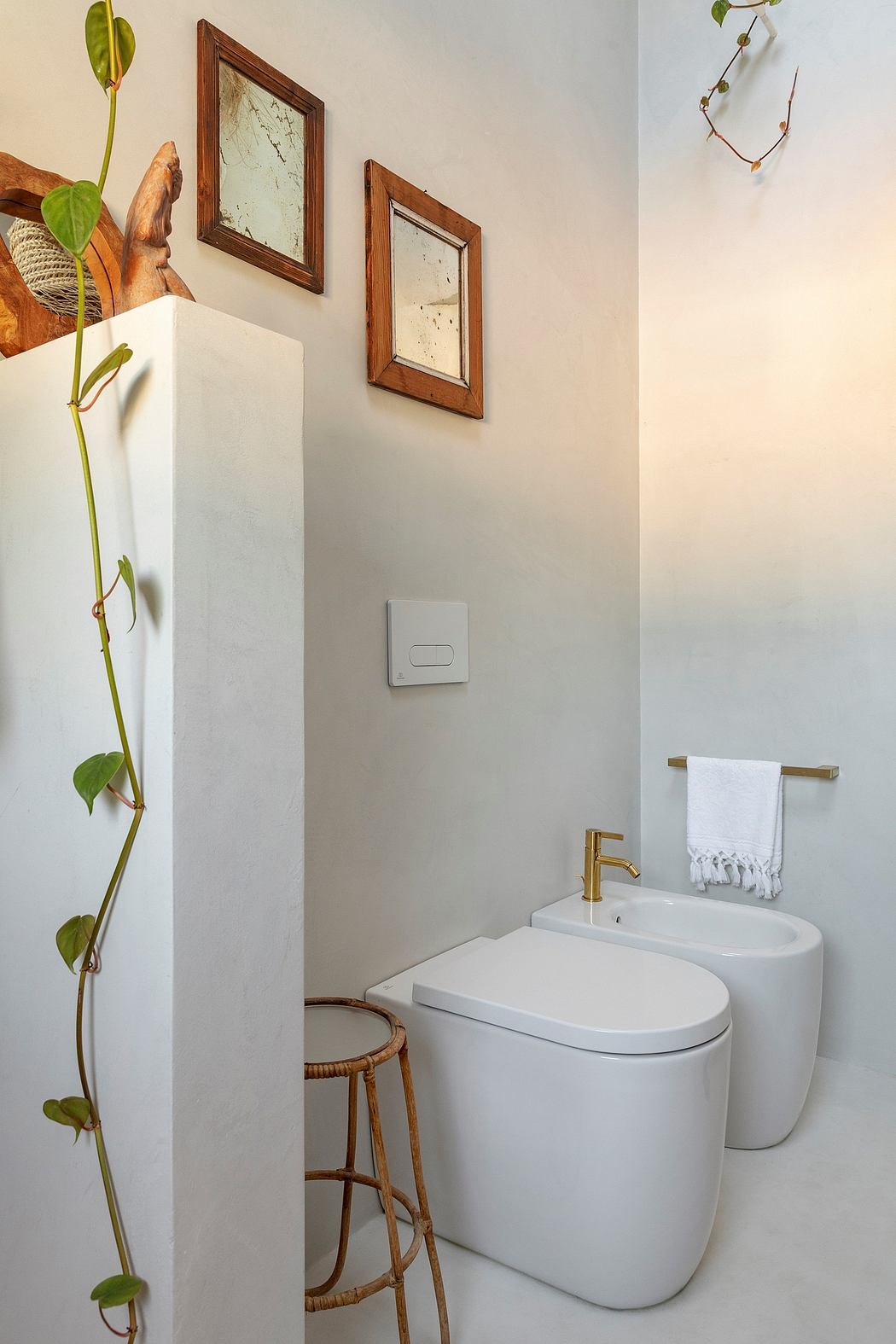 Cozy bathroom with wooden-framed mirrors, white fixtures, and a plant accent.