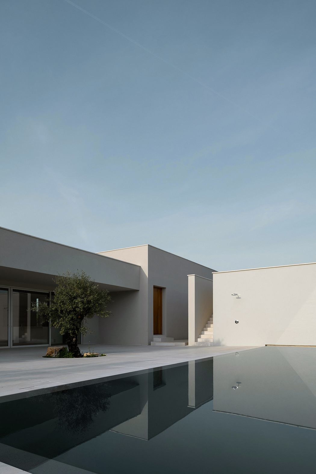 Modern architectural exterior with sleek geometric forms, reflecting pool, and minimal landscaping.
