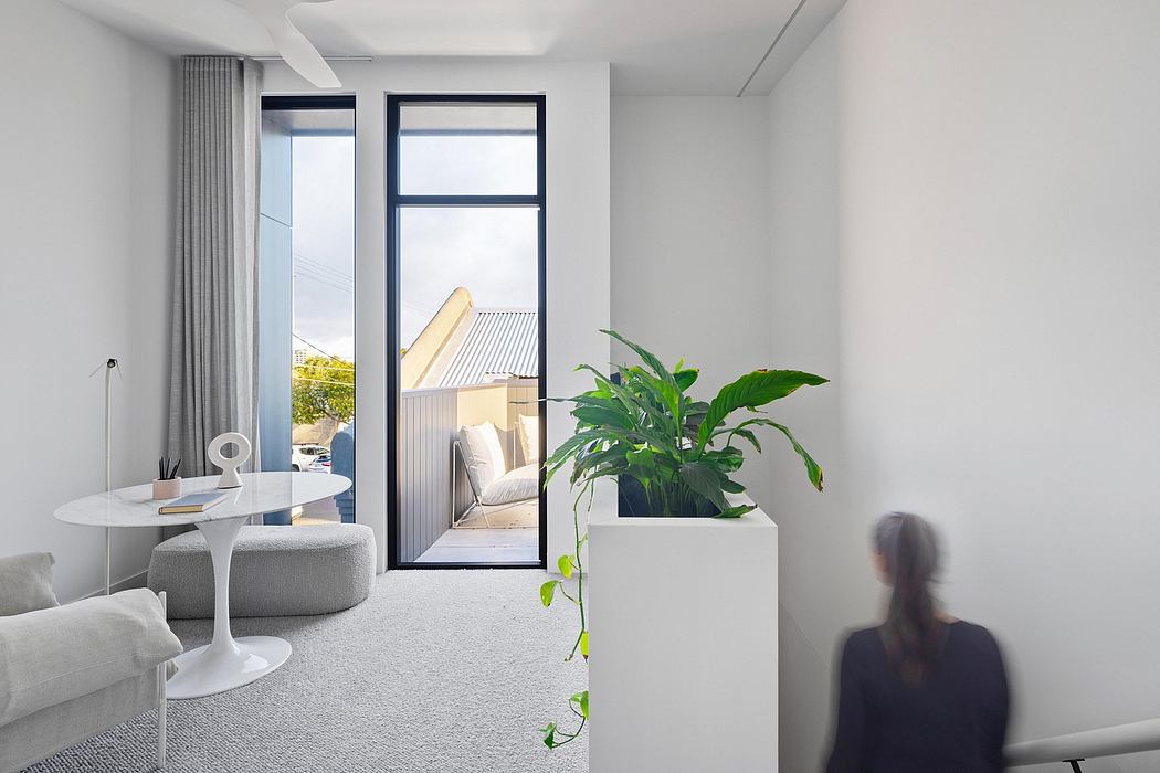 Minimalist living room with large windows, potted plants, and modern furniture.