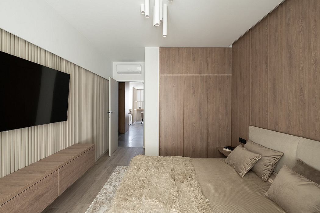 Minimalist bedroom design with wood paneling, large TV, and furry rug.
