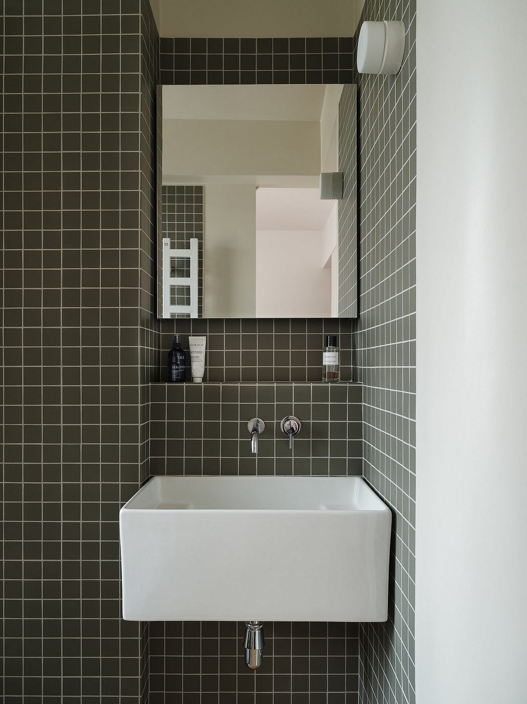 Minimalist bathroom with striking black-and-white tile pattern, floating vanity, and recessed mirror.